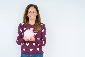 Middle age woman holding piggy bank over isolated background with a happy face standing and smiling with a confident smile showing teeth