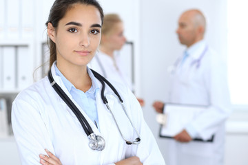 Fototapeta premium Portrait of young doctor woman in hospital. Hispanic or latin american staff in medicine