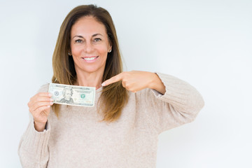 Middle age woman holding 20 dollars bank note over isolated background very happy pointing with hand and finger