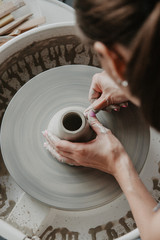 Fototapeta na wymiar Creating a jar or vase of white clay close-up. Woman hands making clay jug.