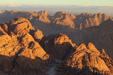 Fototapeta na wymiar Picturesque sunrise at Sinai Mountain (Mount Horeb, Gabal Musa, Moses Mount). Sinai Peninsula of Egypt. Thick fog in the background. Pilgrimage place and famous touristic destination