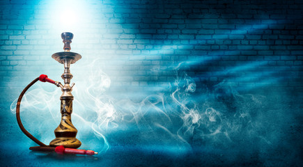 Smoking a hookah against a brick wall, concrete floor, blue  neon light, smoke