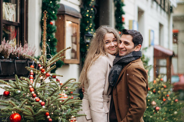 Beautiful romantic lovely smiling couple near Christmas decorations outside