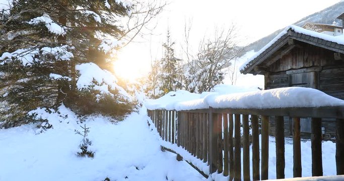 sunrise over snow covered hut and frence in winter