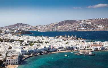 panoramic view of the Mykonos town harbor with famous windmills from the above hills on a sunny...