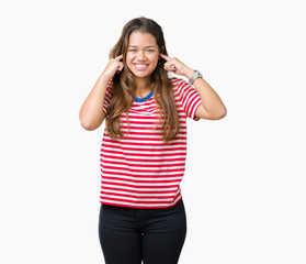 Obraz na płótnie Canvas Young beautiful brunette woman wearing stripes t-shirt over isolated background covering ears with fingers with annoyed expression for the noise of loud music. Deaf concept.