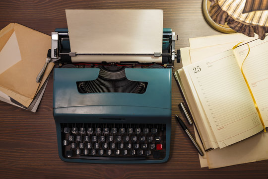 Top view of vintage typewriter with blank paper sheet, documents, diary. Writer or editor in vintage office concept.