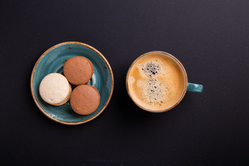 Blue cup of coffee and macaroons on the dark wooden table. Coffe break. Top view. Flat lay