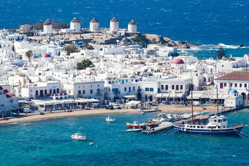 panoramic view of the Mykonos town harbor with famous windmills from the above hills on a sunny summer day, Mykonos, Cyclades, Greece - obrazy, fototapety, plakaty