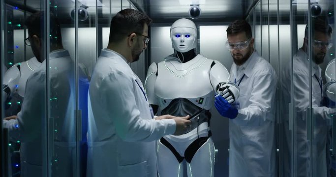Two engineers in protective suits test the robot in the data center by controlling the movements of the hands on the tablet via the user interface.