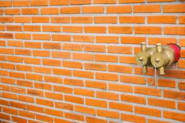 Gold red fire hydrant in the brick wall at modern building