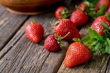 Close-up shot of ripe red strawberries with leaves on a aged rustic wooden desk.