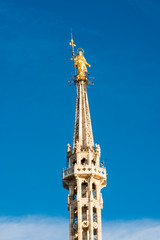 Fototapeta na wymiar Golden statue of Virgin Mary called Madonnina, placed on the roof of Duomo cathedral, is the symbol of Milan, Italy