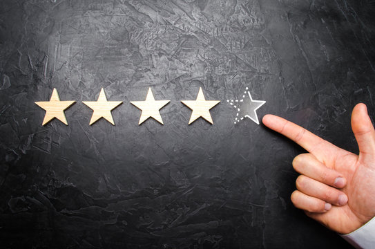 The man's hand in the suit points to the fifth missing star. Concept acquires the fifth star rating or status. Increase prestige and recognition. Rating of hotels and restaurants, shops.