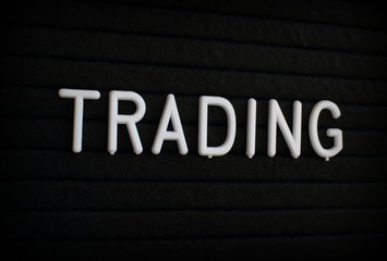 The word Trading in white plastic letters on a black letter board 
