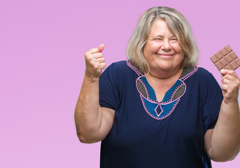 Senior plus size caucasian woman eating chocolate bar over isolated background screaming proud and celebrating victory and success very excited, cheering emotion