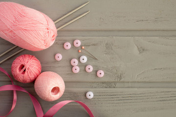 Pink knitting and knitting needles on the grey wooden background.Top view.Copy space.