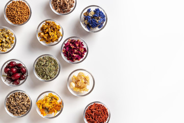 Dried herbs in bowls on a white background with copy space, top view