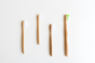 High angle view of four bamboo toothbrushes on white background