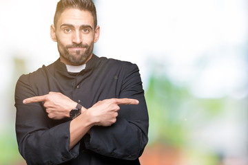 Young Christian priest over isolated background Pointing to both sides with fingers, different...