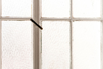 Photo of a white framed window with an old handle.