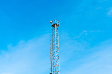 Photo of a metal watchtower with lamps on a sunny day.