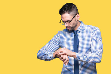 Young business man wearing glasses over isolated background Checking the time on wrist watch, relaxed and confident