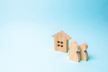 three figures of people and a wooden house on a blue background. The concept of affordable housing...