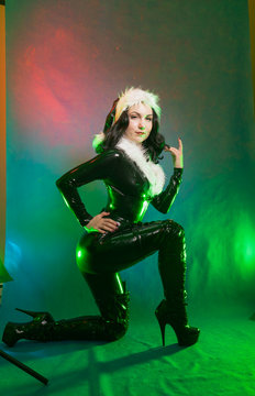 bad kinky black satna girl posing in latex rubber costume with white fur on dark colorful studio background