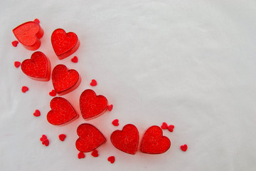 Valentines day concept. Small red plastic hearts with bright dots and tiny red hearts on a white background. Top view.