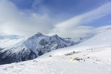 Fototapeta na wymiar Snow cliffs of the peaks of the main Caucasian ridge near the resort ski village Dombay