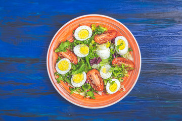 Salad with lettuce, eggs, tomatoes and sesame in orange plate