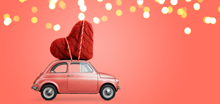 Living coral retro toy car delivering craft heart for Valentine's day on coral background