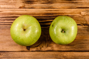 Two ripe green apples on a wooden table. Top view