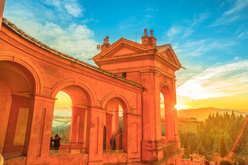 Side view of Sanctuary of Blessed Virgin of San Luca and Colle della Guardia above city of Bologna. Scenic sunset light. Famous landmark cityscape in Emilia-Romagna, Italy.