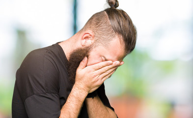Fototapeta premium Young blond man wearing casual t-shirt with sad expression covering face with hands while crying. Depression concept.