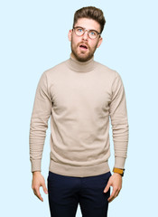 Fototapeta premium Young handsome business man wearing glasses In shock face, looking skeptical and sarcastic, surprised with open mouth