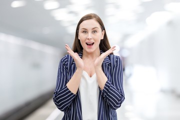 Portrait of an emotional girl standing on the metro platform. Background is blurred.