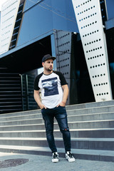 Young man in t-shirt walking near new black building