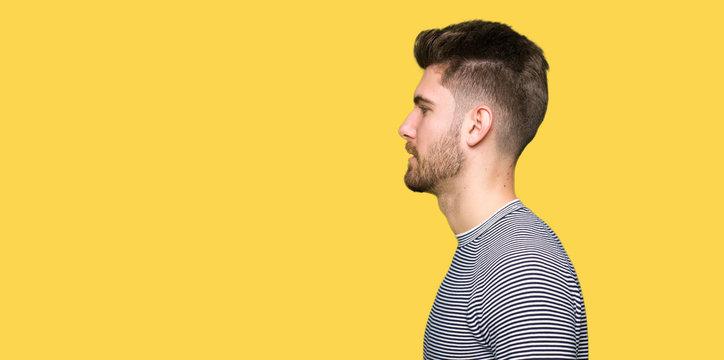 Young handsome man wearing stripes sweater looking to side, relax profile pose with natural face with confident smile.