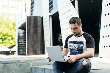 Young freelancer working on street near new contemporary building