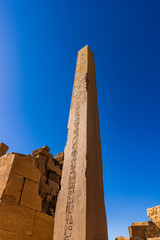 Old ruins with an obelisk with hieroglyphs on the blue sky background in Luxor in Egypt