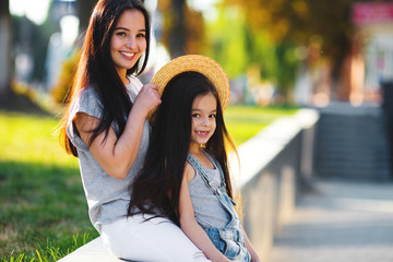 Young mother with cute daughter walking on the street