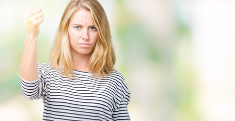 Beautiful young woman wearing stripes sweater over isolated background angry and mad raising fist frustrated and furious while shouting with anger. Rage and aggressive concept.