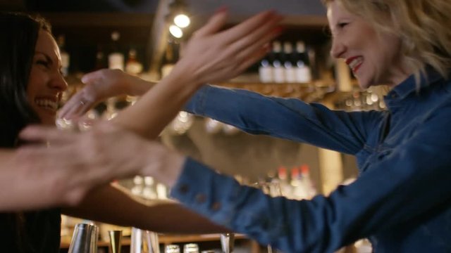 Happy female shows her friend her engagement ring in a bar