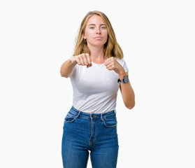 Fototapeta premium Beautiful young woman wearing casual white t-shirt over isolated background Punching fist to fight, aggressive and angry attack, threat and violence