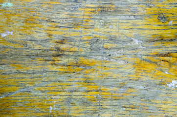 The texture of old wooden board with damaged, shabby and peeling yellow varnish surface