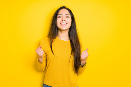 Beautiful brunette woman over yellow isolated background celebrating surprised and amazed for success with arms raised and open eyes. Winner concept.