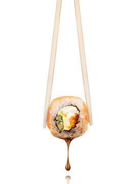 Drop of soy sauce drips from a fresh sushi roll, isolated on a white background
