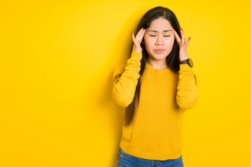 Beautiful brunette woman over yellow isolated background with hand on head for pain in head because stress. Suffering migraine.